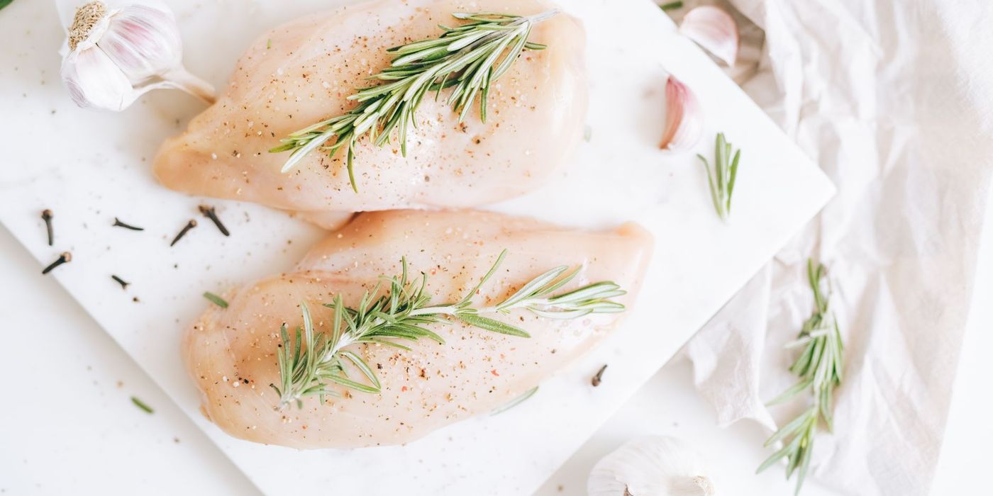 Raw chicken breasts seasoned with rosemary and garlic